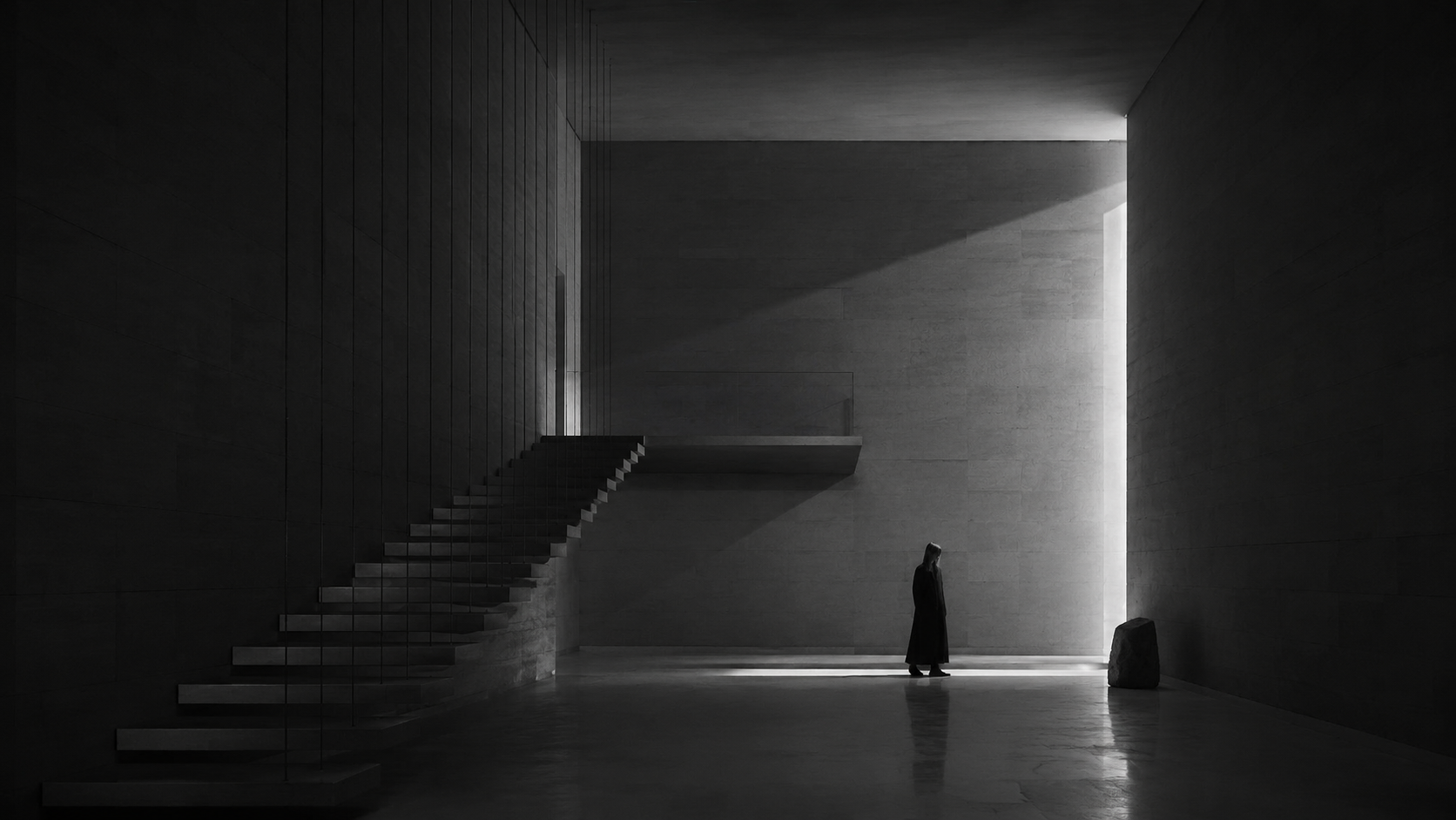Monumental dark architectural interior with a solitary figure beneath a shaft of light